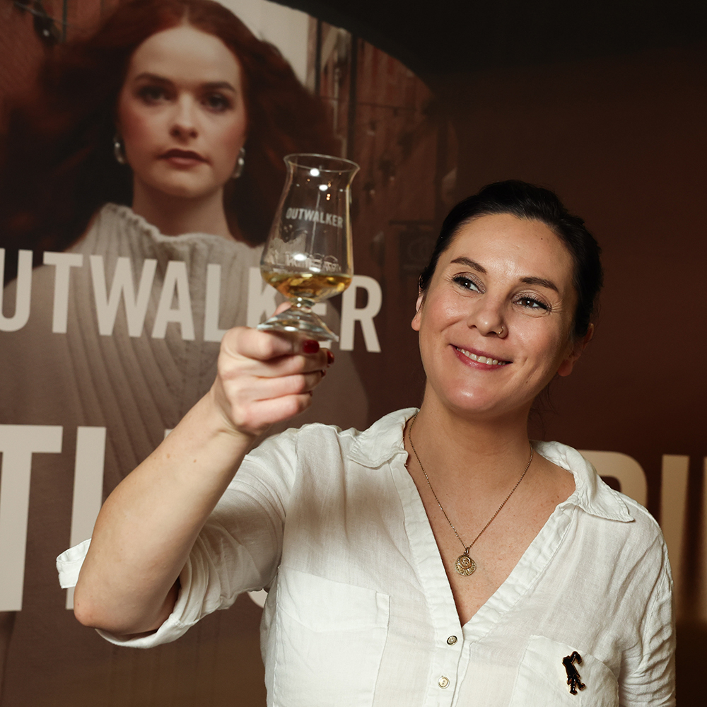 Jillian Vose holding up a dram of Outwalker Whiskey to the light.
