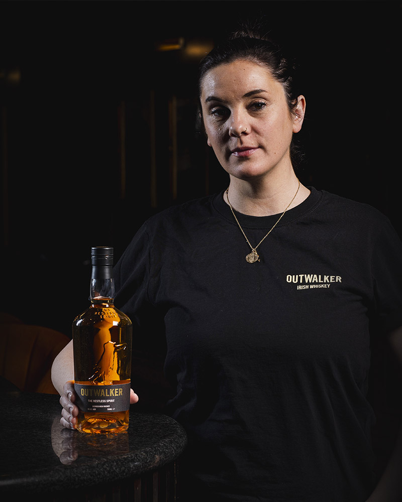 Jillian Vose proudly holding a bottle of Outwalker Whiskey.