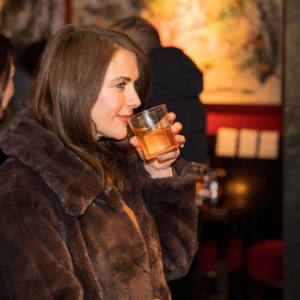 A brunette woman enjoying an Outwalker Whiskey Old Fashioned.